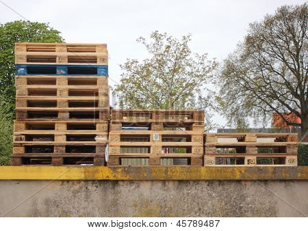 Three Piles Of Wodden Europe Pallets With One In Color