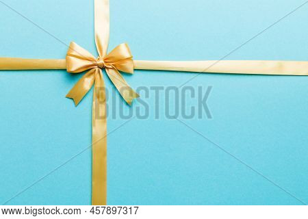 Top View Of Gold Ribbon Rolled And Yellowbow Isolated On Colored Background. Flat Lay With Copy Spac