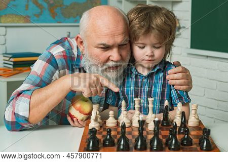 Happy Smiling Grandson Boy With Granddad Playing Chess Together. Happy Family. Two Men Generation, G