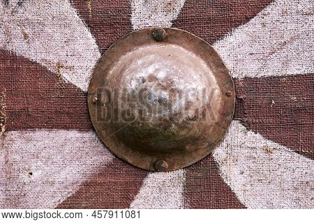 Red Vintage Shild With White Spiral Stripes A Medieval Warrior. Reconstruction Of The Events Of The 