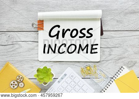 Gross Income Text On A Gray Table On A Light Background Near A Green Plant And A White Keyboard