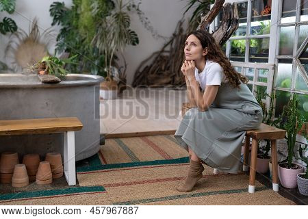 Sad Pensive Woman Sits On Bench In Home Garden Thinking Of Crisis Challenges Looking Out The Window.