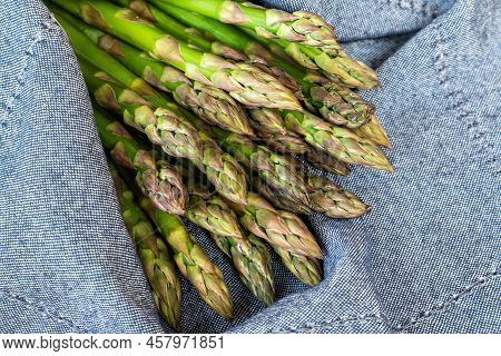 Close-up Detail Bunch Of Fresh Raw Green Asparagus Plant Harvested At Season On Blue Rustic Fabric K