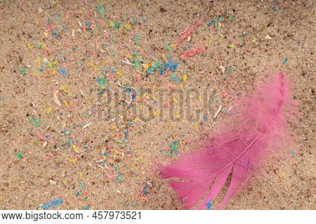 Micro Lastik In The Sand On The Beach, Bird Feather. A Symbol Of Danger For Birds.