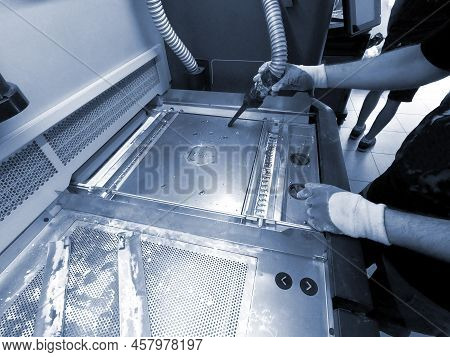 A Male Worker Cleans The Surface Of An Industrial 3d Printer From White Powder With A Vacuum Cleaner
