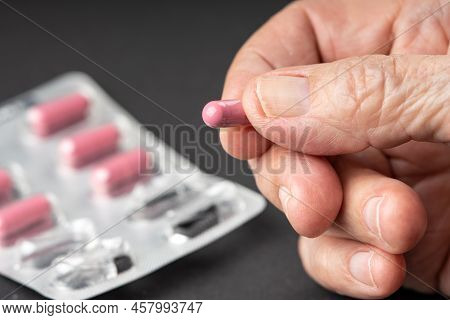 Old Wrinkled Fingers Holding A Pill Close Up.