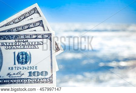 Girl Holding Money Bill Of 300 Dollars On Background Of Sea Ocean Waves And Blue Sky Close-up. Hand 