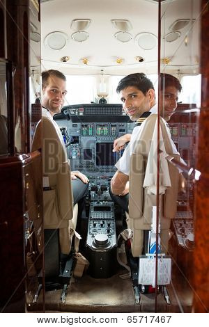 Portrait of confident pilot and copilot in corporate plane cockpit
