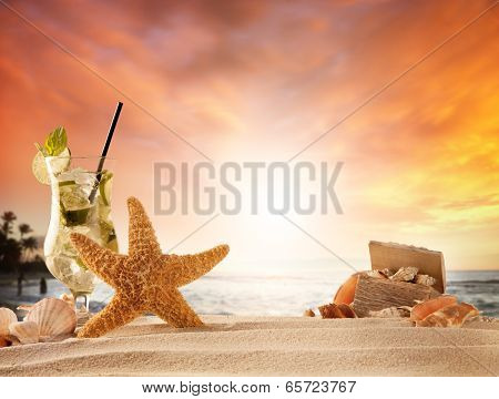 Summer concept with sandy beach, shells and mojito drink