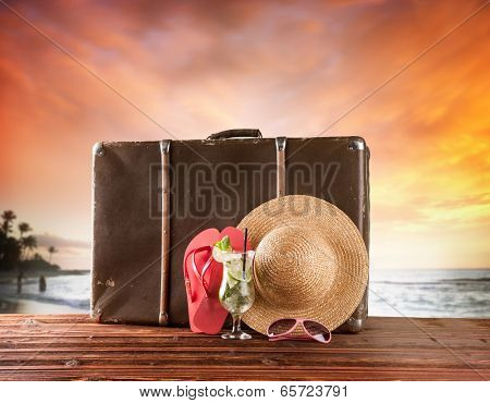 Concept of summer travelling with old suitcase and accessories. Blur beach on background