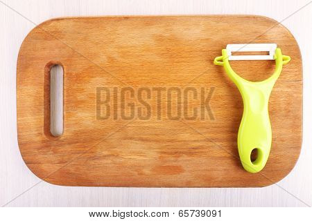 Vegetable peller and cutting board on wooden table