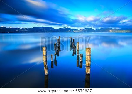 Wooden Pier Or Jetty Remains On A Blue Lake Sunset And Sky Reflection On Water. Versilia Tuscany, It