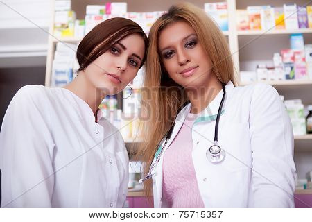Two Nurses In Front Of Pharmacy Desck Smiling