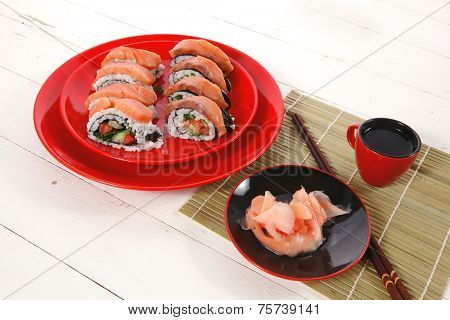 japanese cuisine onigiri sashimi inside out sushi rolls with ginger and sake cup on red plate over white wooden table high resolution hidef
