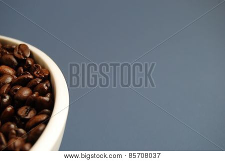 Arabica Coffee Beans in White Bowl Against a Blue Background