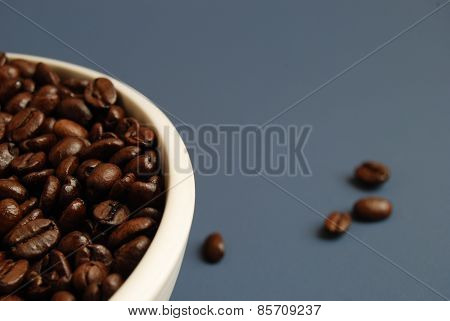 Coffee Beans in White Bowl Against Blue Background