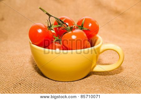 Red Cherry Tomatoes In A Yellow Cup On Old Cloth