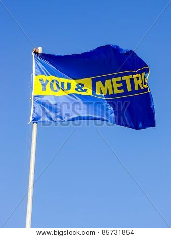 The Promo Flag Of Metro Store Over Blue Sky