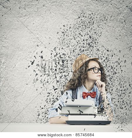 Young funny woman in glasses using typewriter