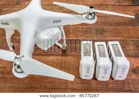 Fort Collins, CO, USA - March 17, 2015:  DJI Phantom 2 quadcopter drone with spare LiPo batteries, top view against rustic wooden table.
