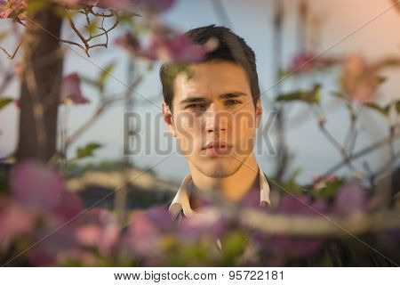 Good looking male model at countryside, among flowers