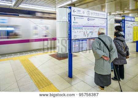 TOKYO, JAPAN - JANUARY 3, 2013: Riders view a subway map as a train approaches at Suitengumae Station.  The station is on the Tokyo Metro Hanzomon Line.