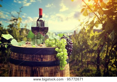 Red wine bottle and wine glass on wodden barrel. Beautiful Tuscany background