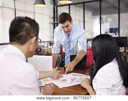 Multinational Businesspeople Discussing Sales Performance In Office