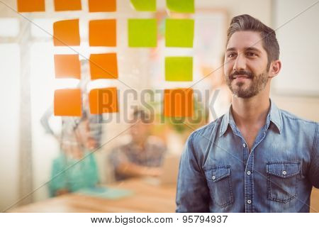 Happy businessman looking post its on the wall in the office
