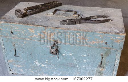 pincers and pliers over old tools for housework, vintage look closed with a padlock, timeworn paint