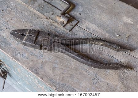pliers over old tools for housework, vintage look, over old wooden toolbox, timeworn paint