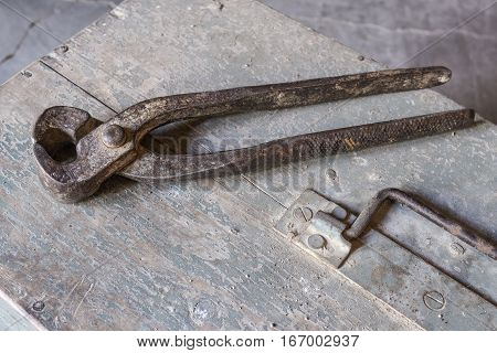 pincers over old tools for housework, vintage look, over old wooden toolbox, timeworn paint
