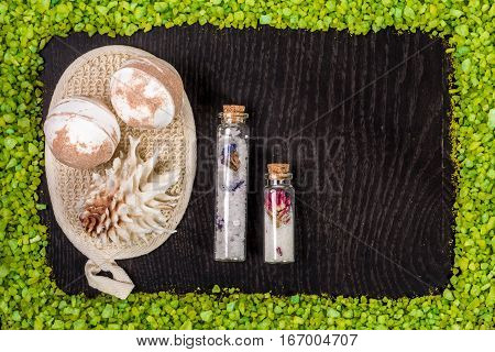 spa set - bombs for bath, sponge, sea salt in small glass jars on black wood table background. Still life. Top view. Copy space