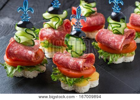 Colorful canape on skewers with vegetables and sausage on a slate plate. Tasty appetizer for a party or banquet. Selective focus