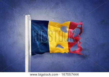 Torn flag of Chad flying against grunge background