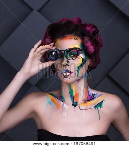close-up fashion faceart portrait of young girl with art painting and lens glass. Amazing creative picture with surrealistic face. Painted background