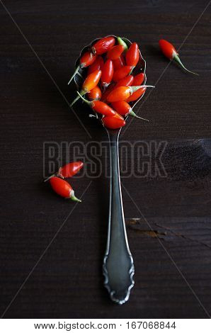 fresh healthy goji berries in front of a brown wooden background