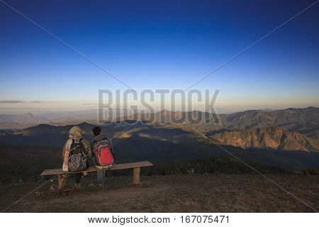 traveling man and woman trekking to top of mountain and relaxing looking to high mountain forward