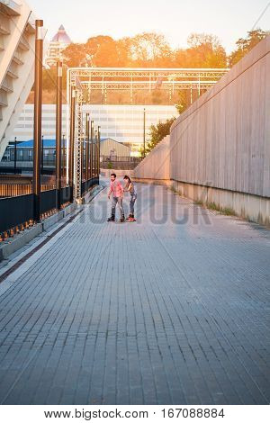 Couple of inline skaters. Two people on wide pavement. Learning to roller skate.