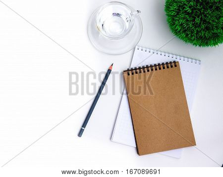 Minimal white office desk table  glass of drinking water and flower pot. Top view with copy space, flat lay.