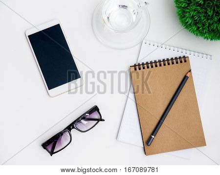 Minimal white office desk table  glass of drinking water and flower pot. Top view with copy space, flat lay.