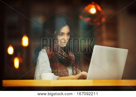 young woman working with laptop in a cafe through the window
