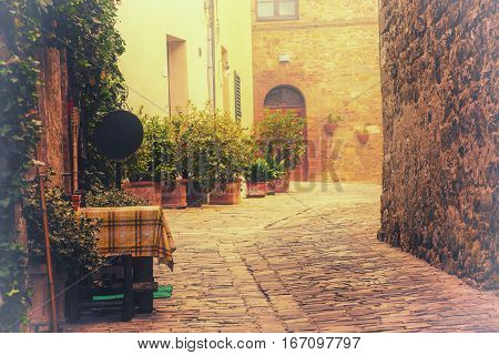 Empty street of small Tuscany town San Quirico d'Orcia in the morning fog, romantic travel vintage hipster european italy background