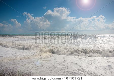 high waves and strong sea tide during a storm under sunny skies