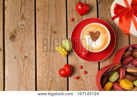 Valentines day concept with macarons and coffee cup over wooden background. Top view from above