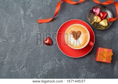 Valentines day concept with coffee cup chocolate and gift box over dark background. View from above