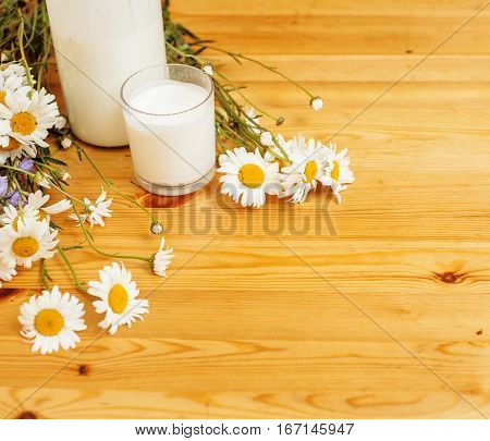 Simply stylish wooden kitchen with bottle of milk and glass on table, summer flowers camomile, healthy foog moring concept noone close up