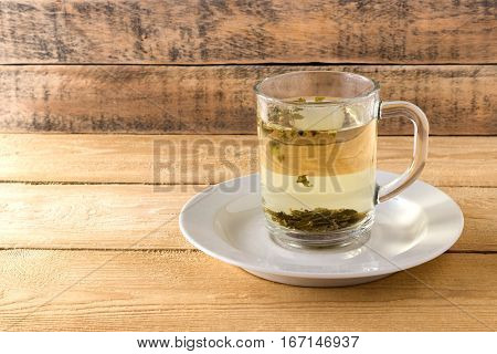 Green tea in a transparent mug on a wooden background