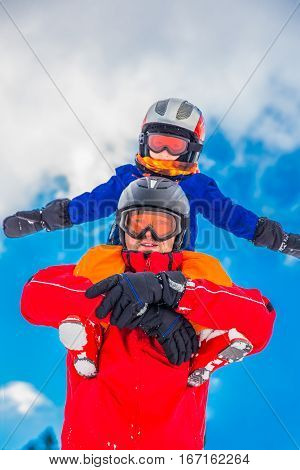 Little boy having fun with his ccaucasian attractive father during skiing in Alps.