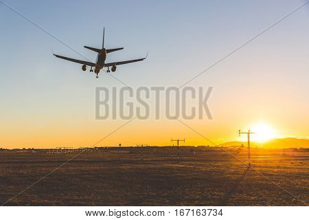 Airplane landing at sunset bottom view. Backlight view of a commercial aircraft on final approach in Mallorca. Wide angle image travel and wanderlust concepts.